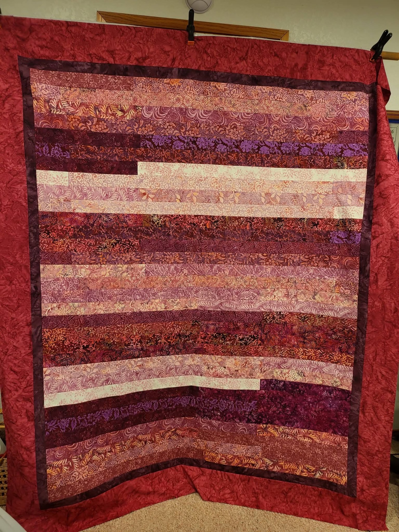 Batik strip quilt in warm red and purple tones